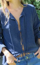 Saco de tejido de punto azul marino, con escote en V y cierre frontal mediante lazos anudados.