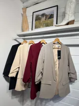 Blazer de corte sastre en color gris claro, con solapas clásicas, bolsillos frontales con solapa y mangas con detalle de frunce.