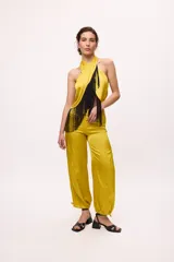 Top de satén color amarillo mostaza con escote halter y flecos negros en el frente.