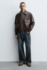 Zapato tipo Mary Jane de hombre, color marrón, fabricado en piel con acabado serraje (gamuza). Presenta cierre con hebilla lateral, detalle de bordón en el empeine y suela gruesa con volumen.