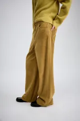 Pantalón de tiro medio confeccionado en tejido de pana, con diseño de pierna ancha, bolsillos delanteros y traseros, y cierre frontal con cremallera y botón.