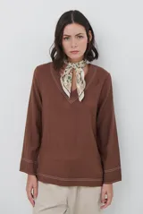 Blusa azul marino de corte recto y holgado, con escote en V y mangas largas. Presenta detalles de costuras a la vista en color blanco en el escote, puños y ruedo.