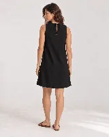 Vestido corto sin mangas de silueta evasé y calce relajado, color negro, con escote redondo, terminación ancha en el ruedo y abertura en la espalda con lazo.