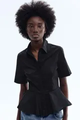 Camisa de manga corta de popelina de algodón en color negro, con cuello camisero, botonadura oculta y diseño con peplum acampanado en la cintura.