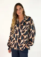 Camisa de manga larga con cuello camisero y cierre frontal de botones, confeccionada en tela fluida con estampado animal print en tonos marrones y negros.