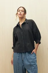 Camisa negra de manga larga con bordados florales en el frente y hombros, detalles de vainillas y botones a tono. Tiene un calce relajado.