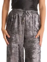 Pantalón wide leg de tela laminada metalizada color blanco, con pretina elástica y lazo de ajuste en la cintura. Cuenta con bolsillos laterales.