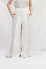 Pantalón de lino color beige y blanco, de corte amplio a la cintura y con bolsillos laterales.