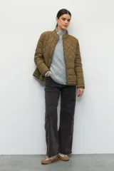 Campera capitoneada color beige, de cuello alto, con bolsillos de solapa y botones metálicos.