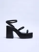 Sandalias negras de charol con plataforma alta y taco cuadrado. Tiras finas sobre el empeine y tobillo con hebilla metálica.