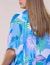 Kimono de gasa azul con estampado botánico de hojas tropicales en tonos celestes, verdes y rosados. Presenta un diseño abierto al frente con mangas cortas y amplias, ruedo asimétrico estilo pañuelo y detalle de borlas en las esquinas inferiores.