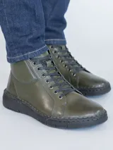 Botines de cuero color verde oliva con cordones negros, suela de poliuretano negra y diseño de caña baja.