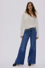 Buzo de punto fino color blanco, con escote amplio tipo barco que deja los hombros descubiertos y remates acanalados en puños y bajo.