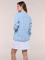 Sobrecamisa azul de denim de algodón liviano, con cuello camisero, cierre frontal de botones, bolsillos con solapa en el pecho y cordón ajustable en la cintura.