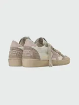 Championes Golden Goose modelo Ballstar, de cuero blanco con detalles en gamuza beige y estrella lateral en color rosa. Presentan un diseño desgastado característico de la marca, con cordones al tono y etiqueta con logo en la lengüeta.