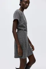 Vestido corto entallado color gris oscuro con cuello redondo, mangas raglán cortas y cierre oculto en la espalda. Incluye un cinturón fino negro con hebilla metálica decorativa.