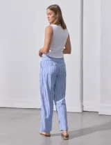 Pantalón de lino estampado a rayas verticales azules y blancas, marca DASH. Tiene pretina ancha elastizada con lazo ajustable.