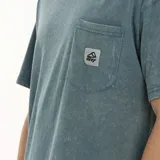 Remera verde oliva de corte oversize, con bolsillo en el pecho y logo de la marca.