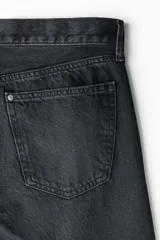 Jean de cinco bolsillos en denim de algodón rígido, color negro con efecto deslavado. Modelo con pierna recta y corte estándar de cintura a bajo, con cierre de botones.