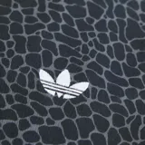 Campera deportiva Adidas Originals modelo Firebird con cierre frontal completo, cuello alto y puños elásticos. Presenta un estampado integral de patrón orgánico en tonos oscuros, con las icónicas tres tiras blancas en los hombros y mangas, y el logo del trifolio bordado en el pecho.