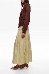 Falda midi de corte en A y silueta fluida, color beige, con diseño de frunces hasta la cadera que aporta movimiento.