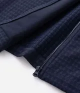 Chaqueta deportiva masculina de color azul marino, confeccionada en tejido técnico repelente al agua con acabado texturizado. Presenta cierre frontal con cremallera, capucha integrada y estampado de coordenadas en el pecho.