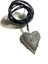 Collar con dije de acero quirúrgico en forma de corazón con diseño de estrella radiante, montado sobre un lazo de cuero negro.