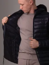 Campera acolchada con capucha de Calvin Klein, color azul marino, con cierre frontal y bolsillos laterales con cremallera. Diseño ligero y funcional con logo de la marca en el pecho.