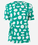 Blusa de viscosa con cuello redondo, manga corta y diseño con nudo lateral. Presenta un estampado geométrico de semicírculos blancos sobre fondo verde.