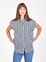 Camisa blanca de manga corta, con cuello camisero y botones frontales. Presenta un corte recto y holgado.