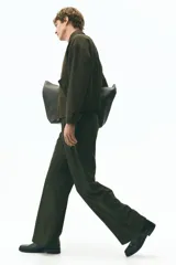 Pantalón de vestir color marrón oscuro, de corte sastrero con pinzas frontales, tiro alto y piernas amplias. Presenta cierre oculto con botón y corchete, bolsillos al bies y bolsillos traseros insertados.