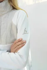 Buzo de algodón blanco con cuello alto, medio cierre frontal y panel superior capitoneado en color beige claro. Cuenta con mangas largas y bolsillos frontales.