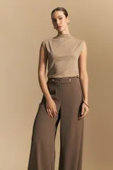 Pantalón ancho color tostado, de silueta fluida y cintura elastizada. Presenta una pretina ancha con botones metalizados irregulares.