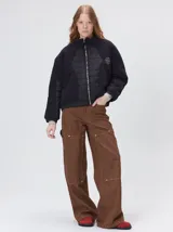 Campera crop de corte boxy y color negro, forrada en corderito, con parches capitoneados en el pecho y las mangas. Cuenta con cierre frontal metálico, cuello alto, puños y bajo elastizados, y detalle de logo bordado en hilo en el pecho.