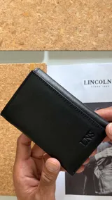 Billetera vertical de cuero negro, con diseño de tres cuerpos, dos divisiones para billetes, ocho espacios para tarjetas y un visor.