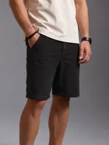 Bermuda de jean color negro con diseño clásico, bolsillos laterales y trabillas para cinturón.