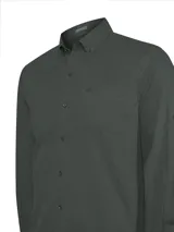 Camisa de manga larga color verde oscuro, confeccionada en popelina de algodón orgánico teñida en prenda. Presenta un bolsillo en el pecho con logo bordado y ruedo redondeado.