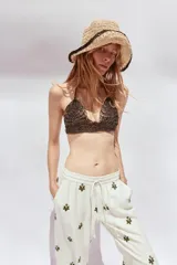 Pantalón color crema de tiro medio con cintura elástica ajustable y bolsillos delanteros. Presenta bordados florales en negro y corte ancho.