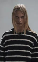 Sweater de cuello redondo con diseño de rayas horizontales en blanco y negro. Confeccionado en tejido de punto con textura suave, corte oversize y terminaciones en punto rib en cuello, puños y ruedo.