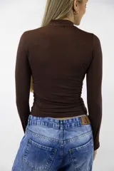 Polera color beige de manga larga y cuello alto, confeccionada en tejido ajustado al cuerpo.
