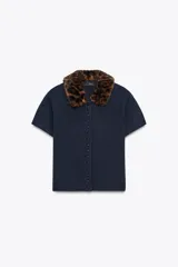 Chaqueta de punto de manga corta en color azul marino, con cierre frontal de botones y cuello solapa con aplicación de pelo sintético con estampado animal.