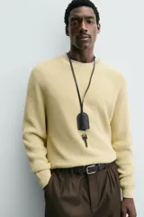 Sweater de punto canalé color beige, con cuello redondo y mangas largas con diseño raglán.