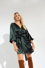 Vestido corto color verde esmeralda de satén, con escote cruzado, mangas largas abullonadas con puños elásticos y lazo en la cintura.