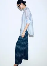 Pantalón de corte recto y tiro regular, confeccionado en algodón con diseño de rayas verticales. Presenta cintura elástica con cordón ajustable y bolsillos laterales.