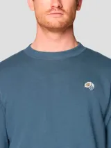 Buzo de cuello redondo color azul, con puños y bajo acanalados. Presenta un pequeño logo bordado en el pecho.