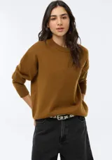 Buzo de punto color marrón, con cuello redondo acanalado, mangas largas con puños ajustados y diseño holgado.
