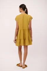 Vestido corto rojo vibrante, estilo babydoll con volados en el ruedo y cuello mao con abertura en V. Presenta mangas cortas tipo capa y un broche de cerezas prendido en el pecho.