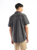 Camisa negra de manga corta con cuello clásico, cierre frontal con botones y dos bolsillos de parche en el pecho. Corte recto y estilo utilitario.