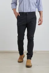 Pantalón de vestir verde oliva, de corte slim fit, sin pinzas, con bolsillos laterales y traseros. Se ajusta a la cintura con cinturón de cuero marrón.