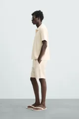 Bermuda azul marino de corte regular fit, confeccionada en tejido de algodón y lino. Cuenta con bolsillos frontales y traseros, cierre frontal con cremallera y botón.